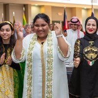 Four people cheering in a room with flags in the background.