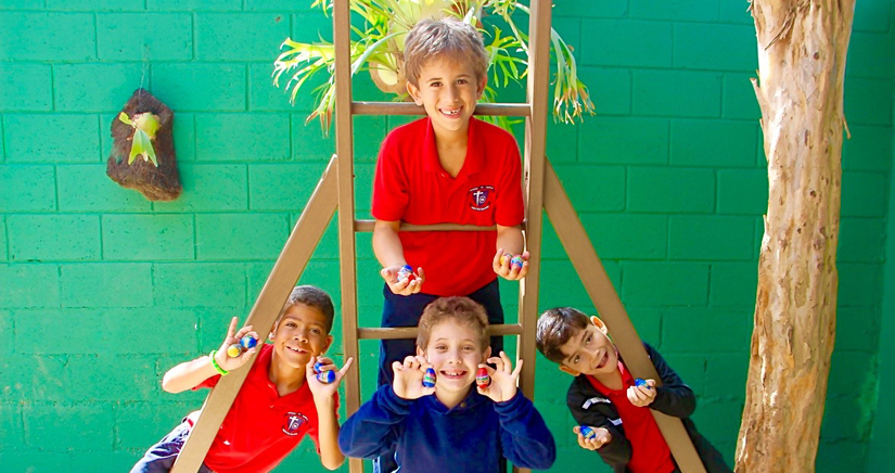 Four elementary-school-aged boys pose in front of a green wall.