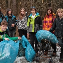 Several student pose together with large trash bags to demonstrate all of the debris they gathered near and in the stream.