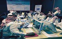 A group of people sit around a table each looking at their own computer.