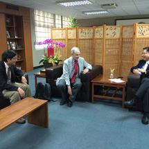 Three men sit and chat together indoors.