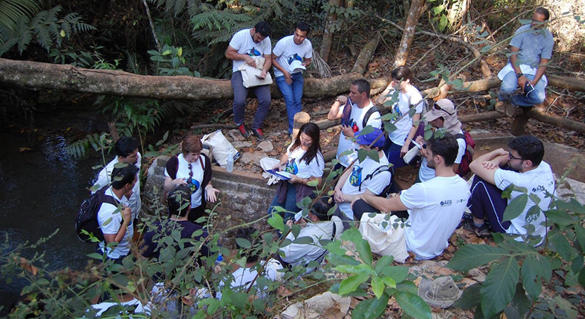 Students and teachers sit near a river.