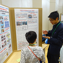 Two boys talk together in front of a poster.