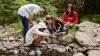 Four students doing hydrosphere GLOBE measurements in a water body in the woods.