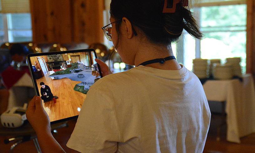 Student holding a tablet with a game pictured on it.