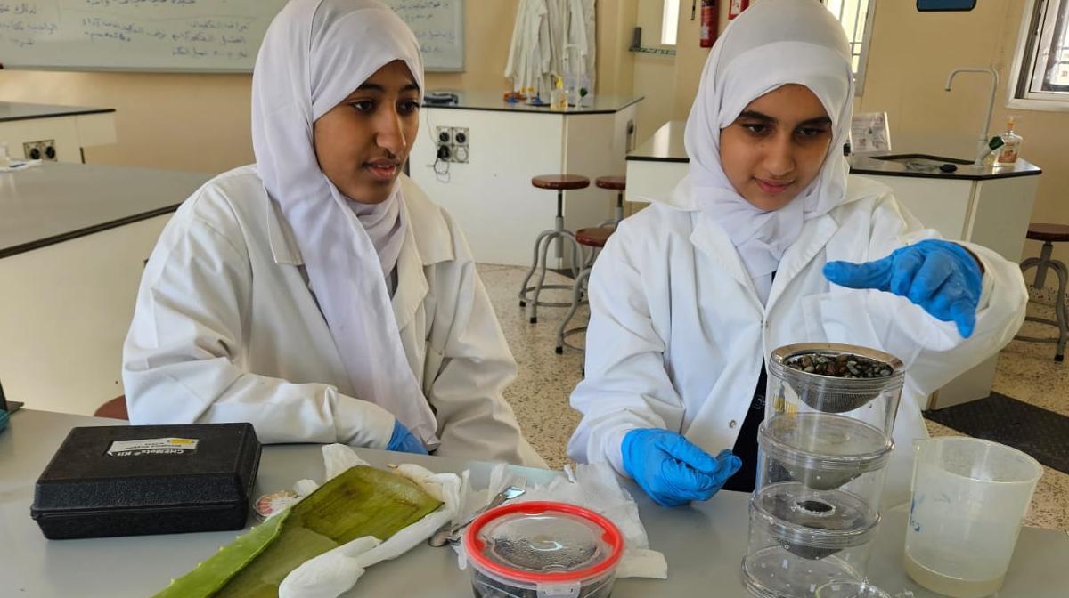 Students purifying water using soil, algae and aloe Vera.