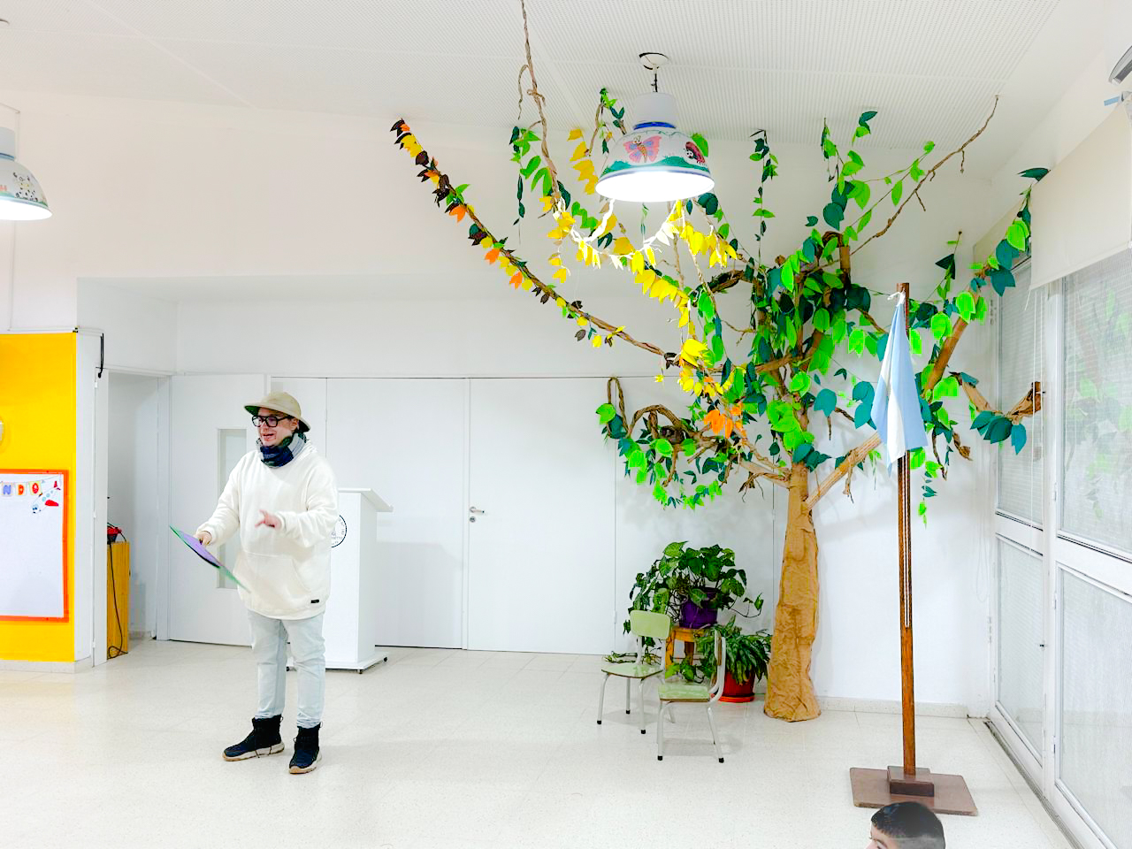 Person talking with a tree made of paper next to them.