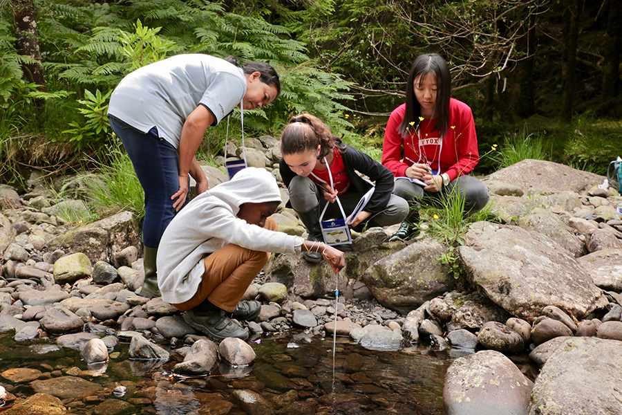 GLOBE students collecting water quality data along a stream.