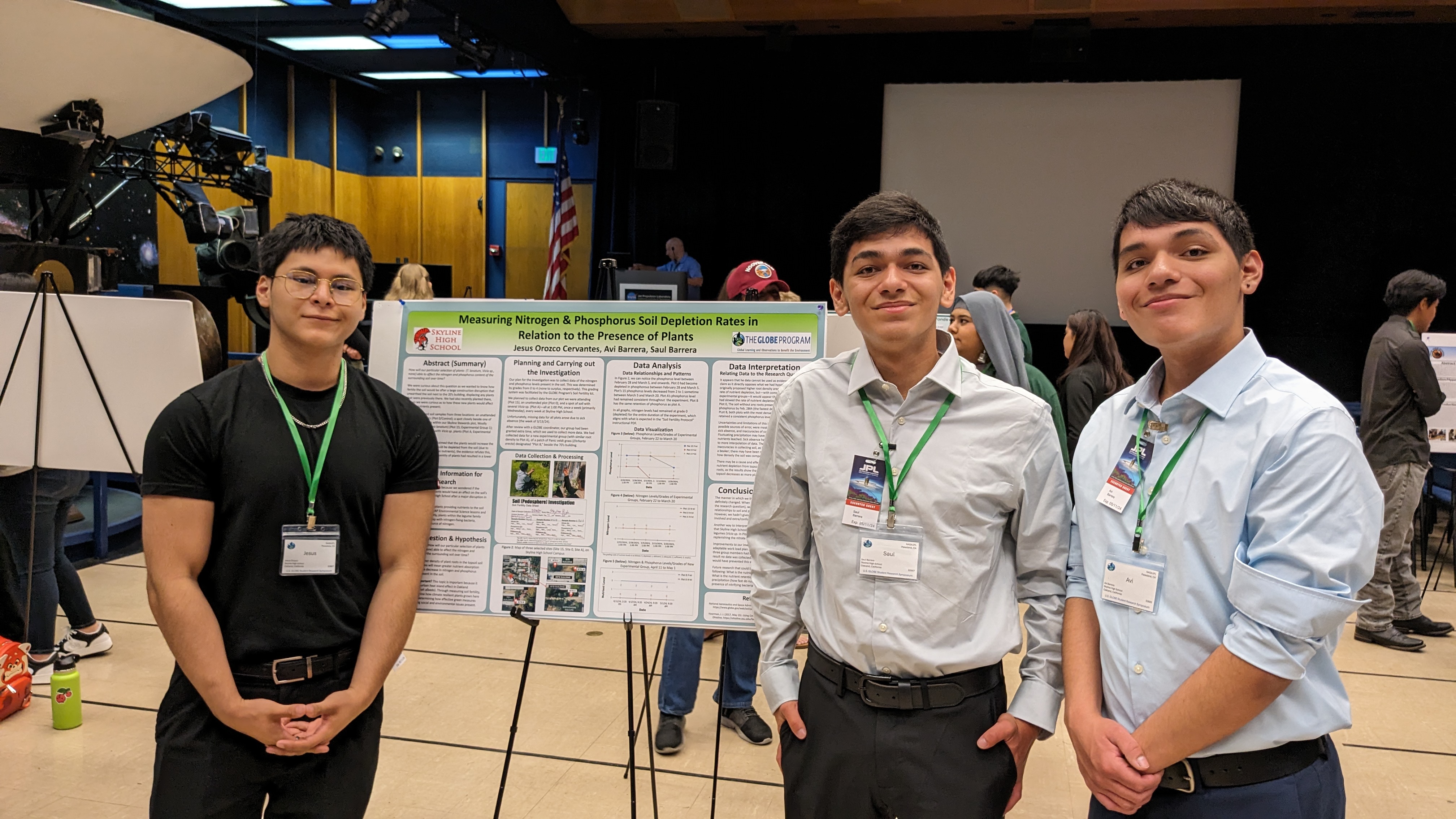 Three students stand in front of their poster