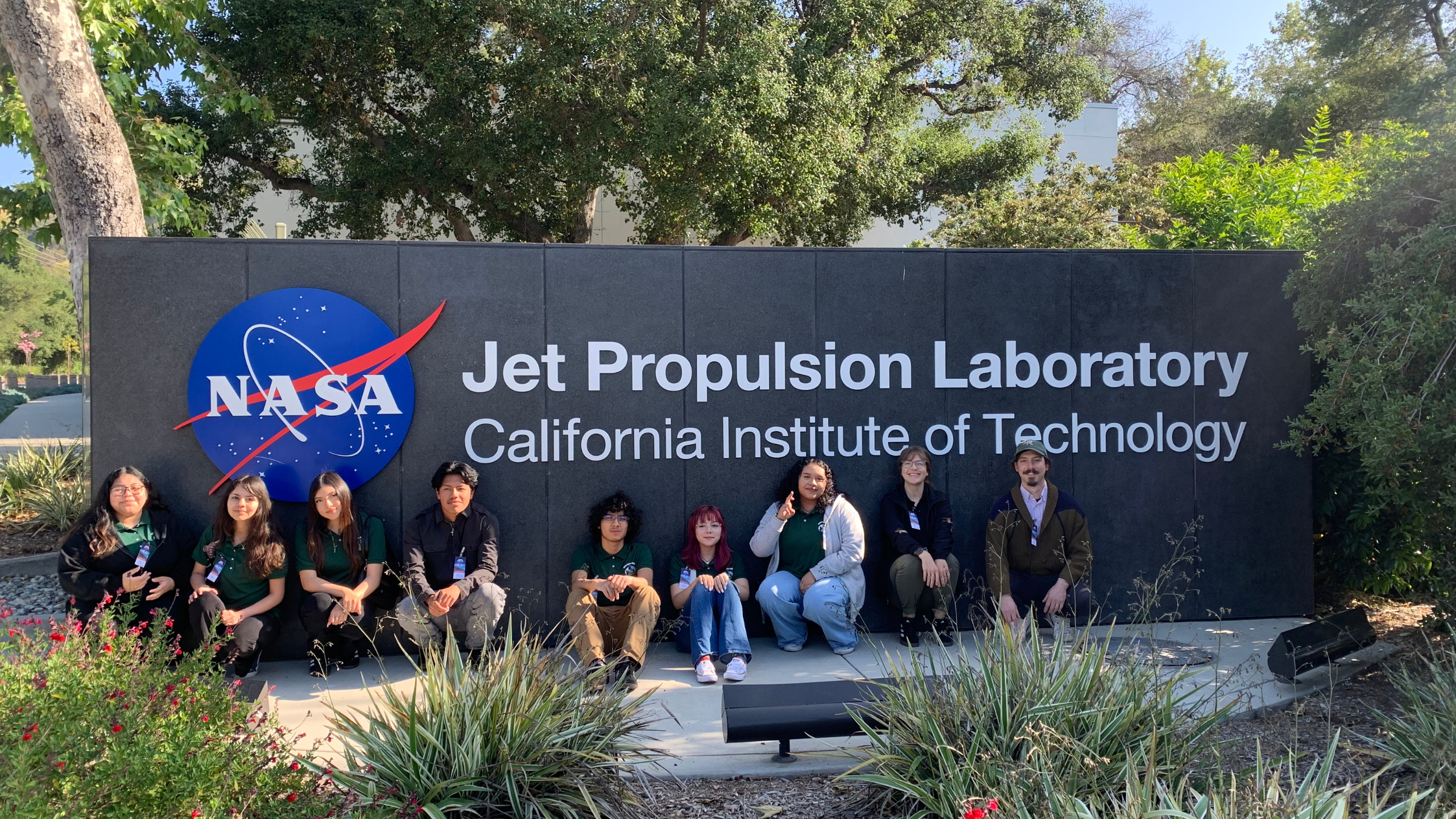 Students and educators from one GLOBE school pose with the Jet Propulsion Laboratory sign in Pasadena, California
