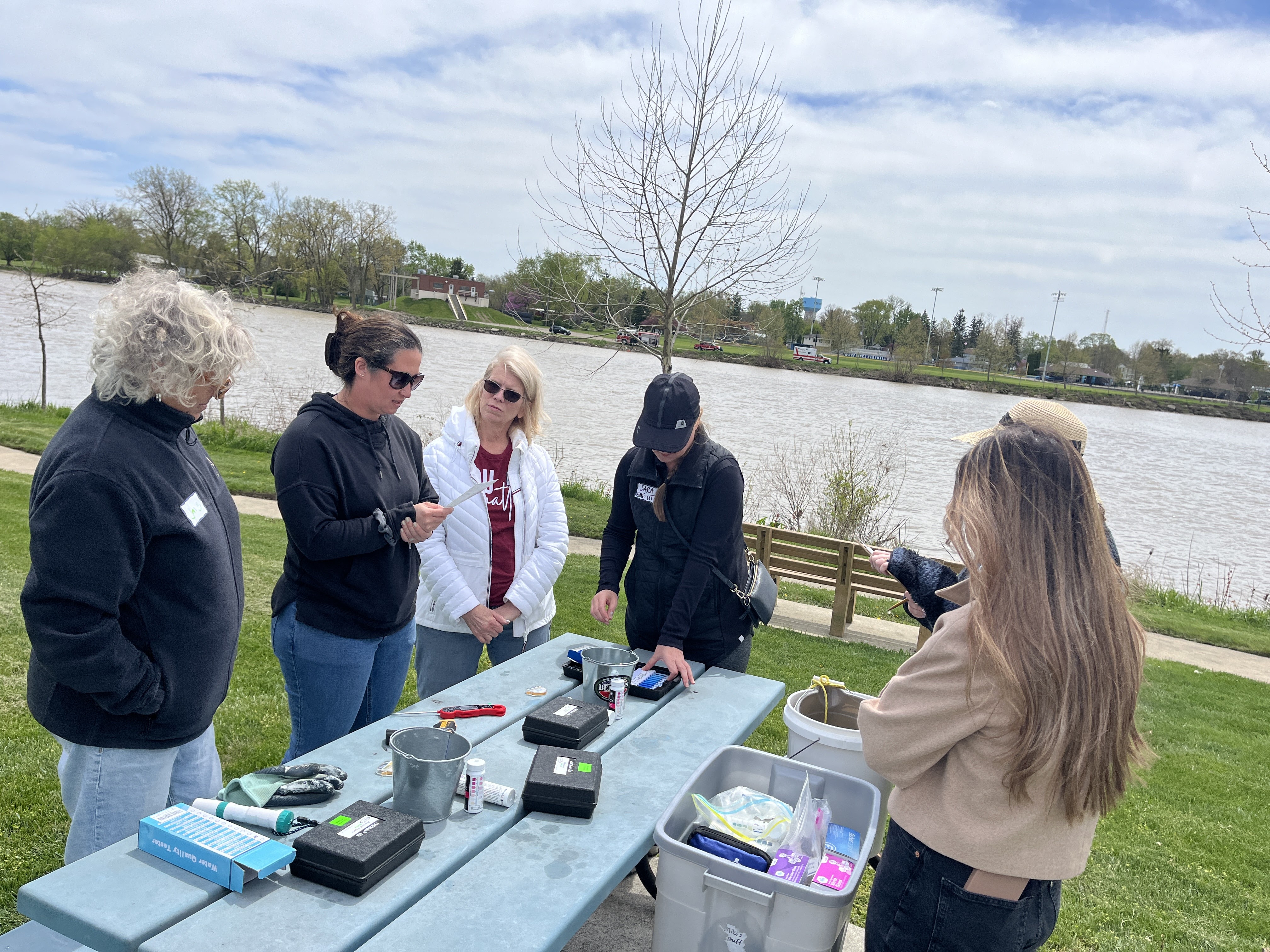 NARM participants stand around a picnic table with various water quality testing kits