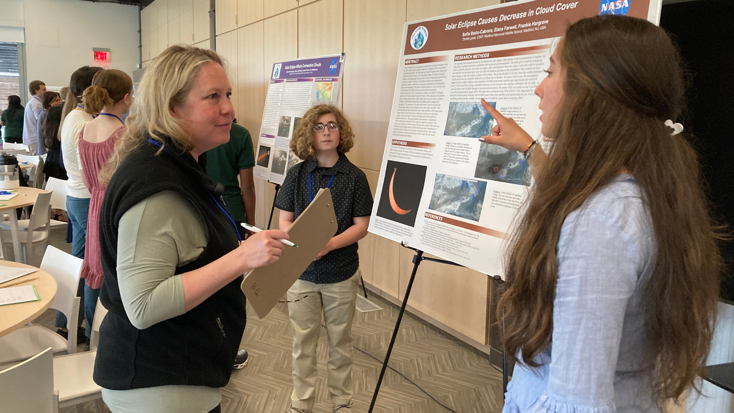 students present their research poster "Solar Eclipse Causes Decrease in Cloud Cover" to a STEM professional at the student research symposium