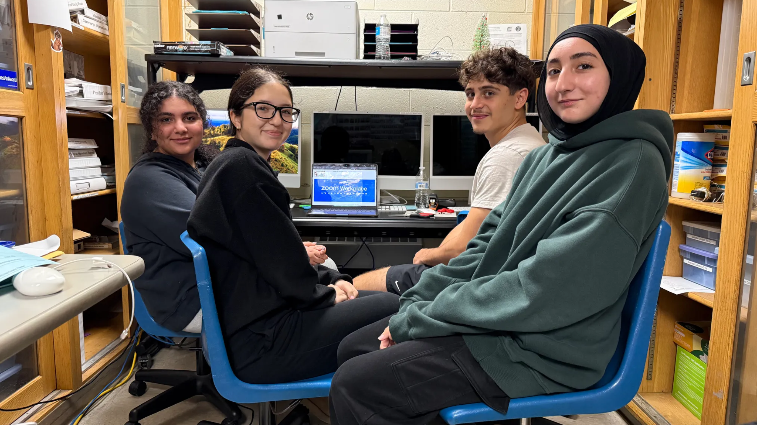 students sit in a a small space to tune into the student research symposium