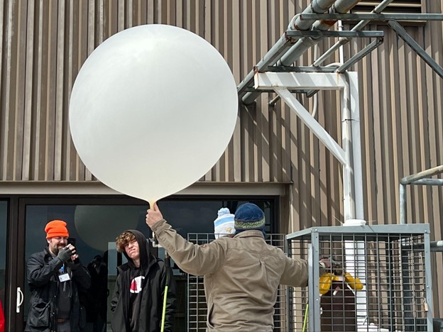 Joe Carstensen and a student watch a demonstration of a weather balloon