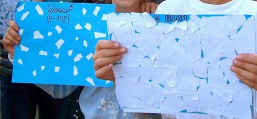 Niños sosteniendo hojas de papel azules que tienen trozos de papel blanco encima.