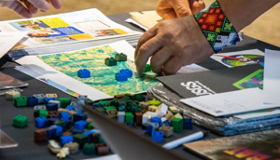 A tabletop set up with activities, including a hand using LEGO bricks to represent land cover type.