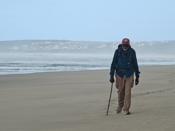 Dr. John Francis walks along a beach in South Africa