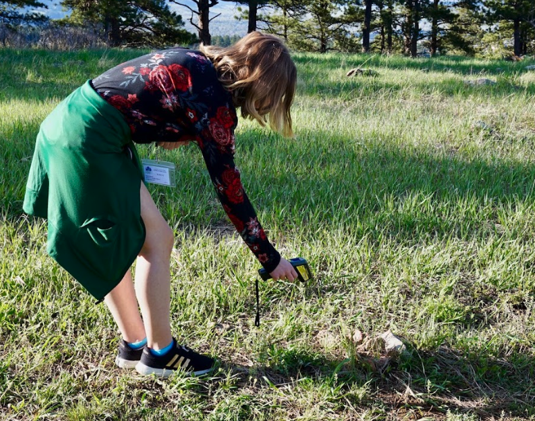 a student measures surface temperature on a grassy area